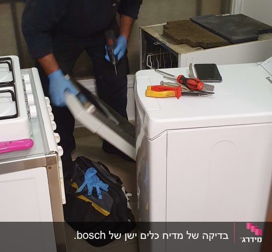 טכנאי עם מסכה מתקן מכונת כביסה עם כלים